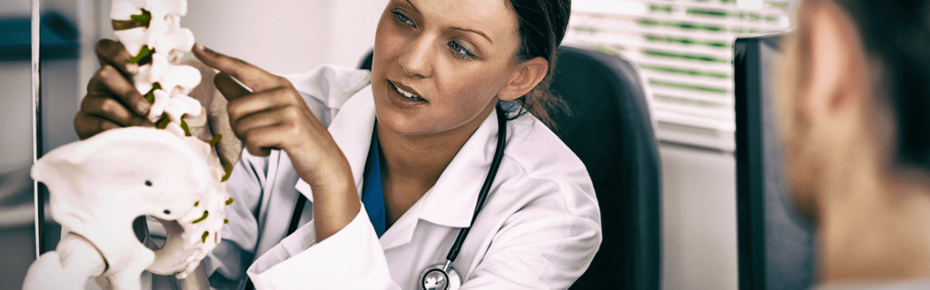 doctor pointing to model of healthy spine