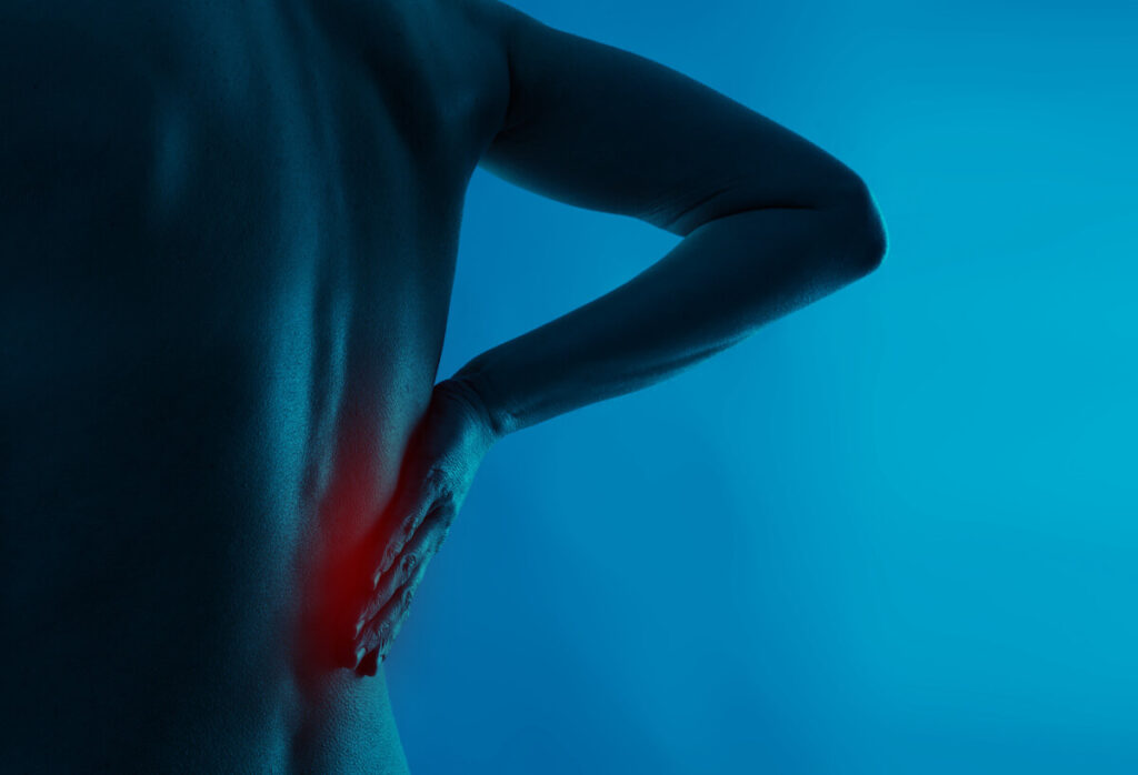 holding lower back in pain with the pain area highlighted red